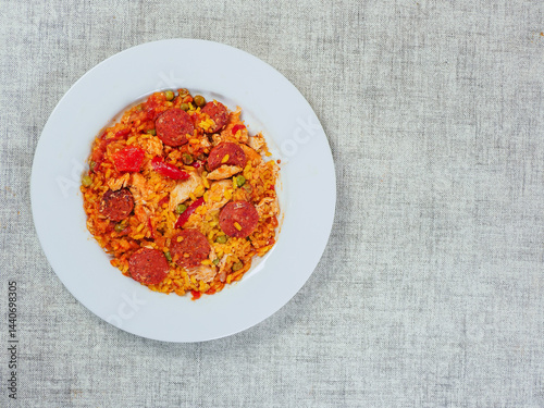 Obraz na płótnie Fine tasty Spanish paella dinner with rice and high quality chorizo sausage on white plate and simple table cloth. Mediterranean style dish. Popular food made from premium ingredients. w salonie