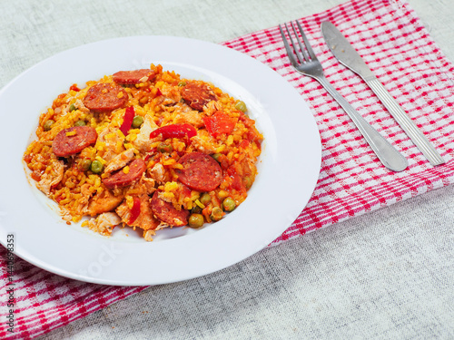 Obraz na płótnie Fine tasty Spanish paella dinner with rice and high quality chorizo sausage on white plate and simple table runner. Mediterranean style dish. Popular food made from premium ingredients. w salonie