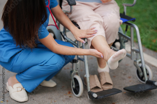 Asian physical therapist nurse is performing physical therapy to rehabilitate the legs of an elderly female patient.