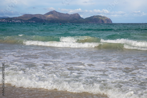 Fototapeta Naklejka Na Ścianę i Meble -  Mediterranean beach on the island of Majorca, or Mallorca on Balearic Sea, are part of Spain. Island in the Mediterranean Sea. Seaside vacations, clouds, seascape. View of the sea and the island.  