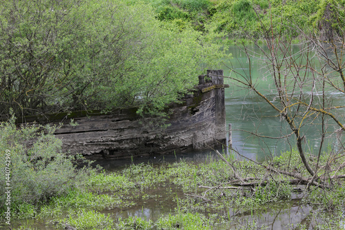 Obraz na płótnie Bow of th sunken boat called BURCIO or BURCHIO in italian language in the BURCI CEMETERY a place in the bend of the river SILE in Northern Italy with wrecks of old sunken boats and trees w salonie