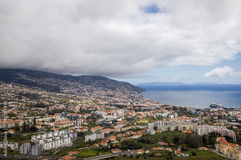 Views of Funchal, Madeira showcasing coastal cityscape and lush hills under cloudy skies