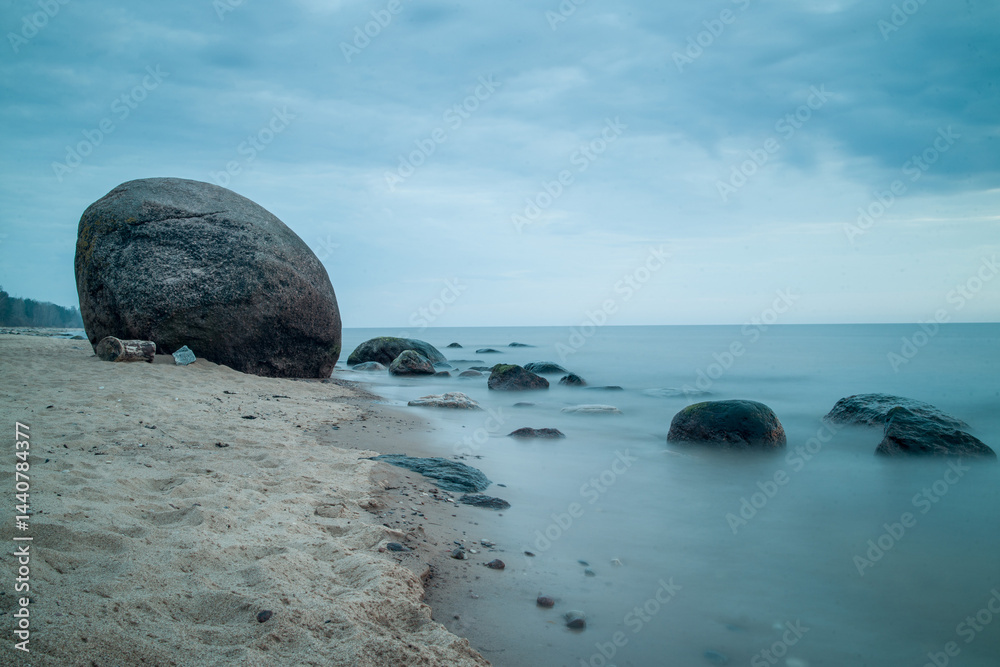 Stunning Laucu stone by the calm Baltic Sea shoreline in Latvia during a tranquil overcast day