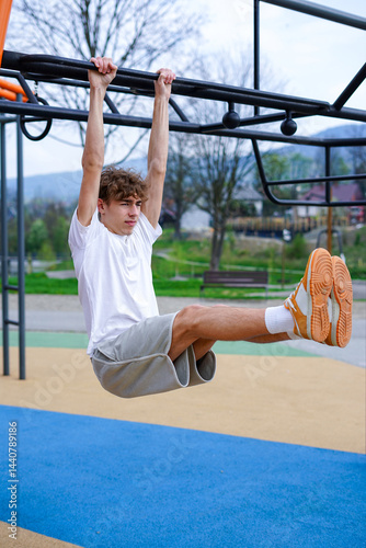 Young Man Doing Hanging Leg Raise Workout Outdoors. Athletic man performs hanging leg raises on an outdoor fitness bar