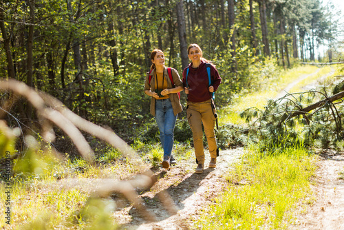 Joyful friends hiking together on a sunny trail surrounded by lush greenery in a vibrant forest in autumn