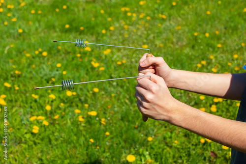 Dowsing rods metal indicator in hands. Modern Divining L rods steel cylinder resonator for Bio location. An ancient method unproven by science