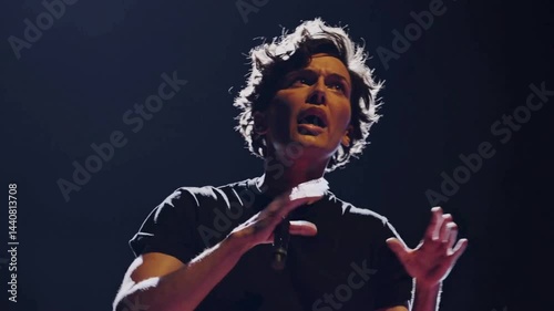 Male performer standing barefoot under dramatic theater spotlight