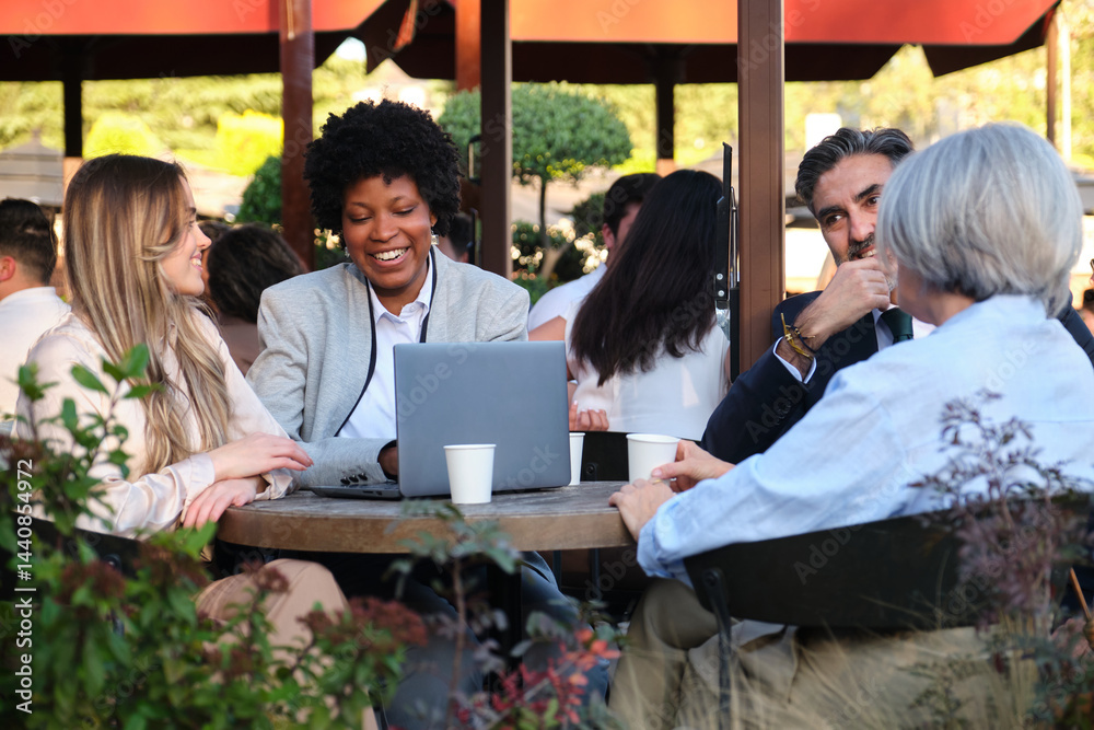 Businesspeople working on a laptop and having a meeting at an outdoor cafe