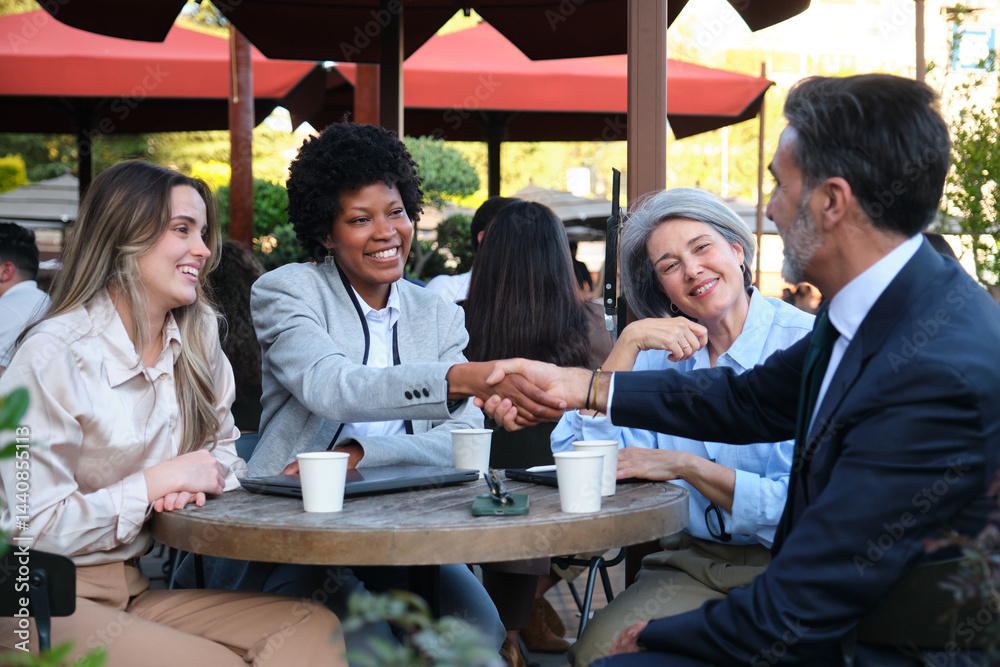 Business partners shaking hands after closing a deal at a coffee shop