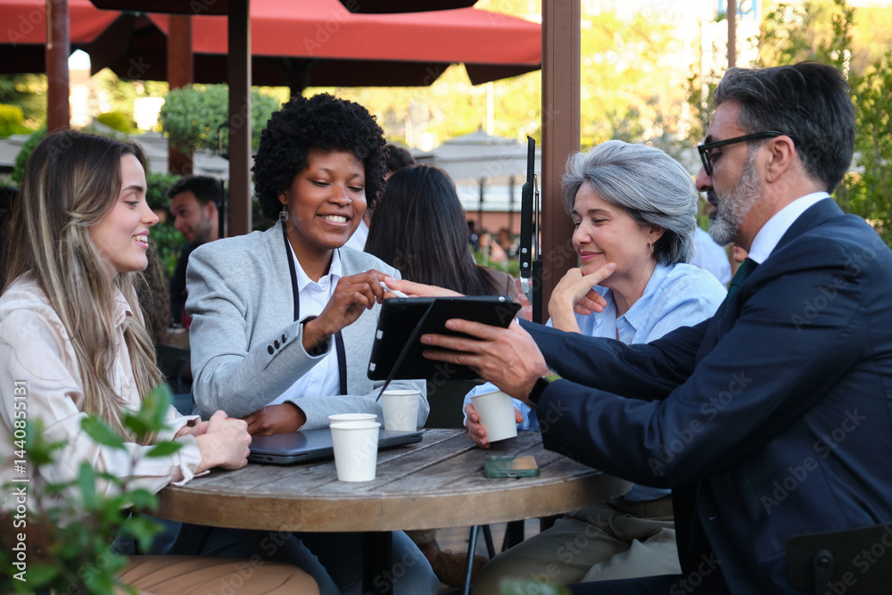 Businesspeople using tablet and laptop during a meeting at outdoor cafe