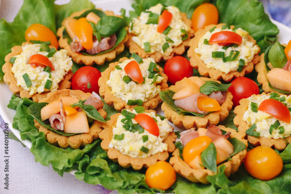 Delicious savory tartlets with egg salad. Fresh appetizers on lettuce. Colorful snack with vegetables. Tasty party food. Homemade finger food. Light summer refreshment. Festive table decoration.