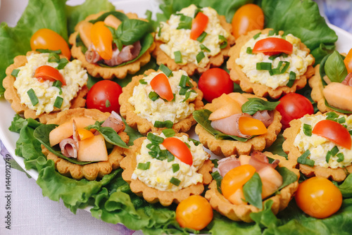 Obraz na płótnie Delicious savory tartlets with egg salad. Fresh appetizers on lettuce. Colorful snack with vegetables. Tasty party food. Homemade finger food. Light summer refreshment. Festive table decoration. w salonie