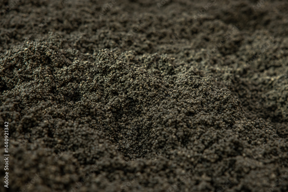 Detailed view of a rugged surface composed of small, dark granules with uniform size and color, highlighting the texture and uneven appearance.