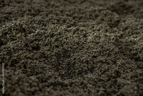Obraz na płótnie Detailed view of a rugged surface composed of small, dark granules with uniform size and color, highlighting the texture and uneven appearance. w salonie