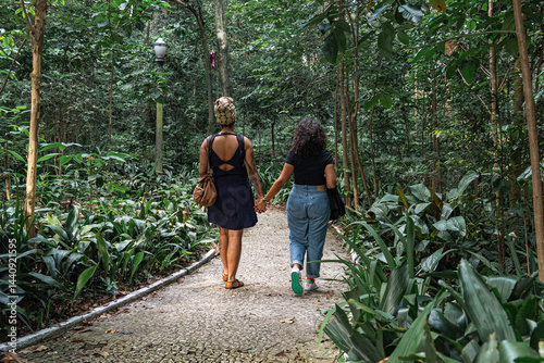 Back view of lesbian couple walking hand in hand in São Paulo park