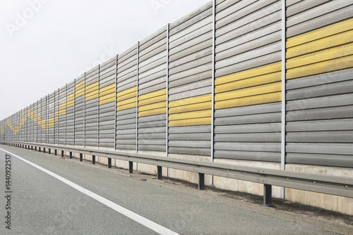 Obraz na płótnie Modern highway sound barrier. Long noise protection wall. Urban infrastructure design. Gray and yellow panels. Roadside safety concept. Contemporary architectural structure. Silent travel environment. w salonie