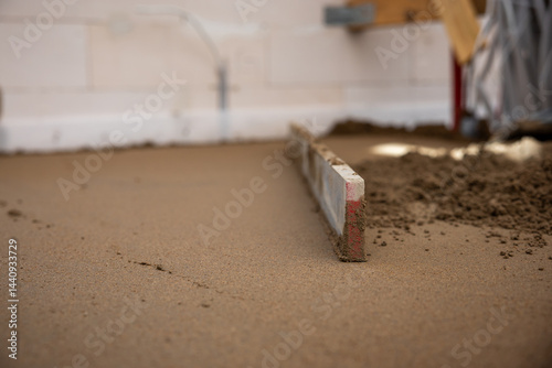 Obraz na płótnie A screed tool levels freshly laid Estrich concrete indoors, with white walls, electrical outlets, and cables visible in the background. w salonie