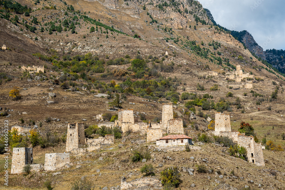 Ancient stone towers and buildings in mountainous landscape. Ruins of old village built into hillside. North Caucasus mountainous Ingushetia Russia Historical ruins in mountainous landscape.