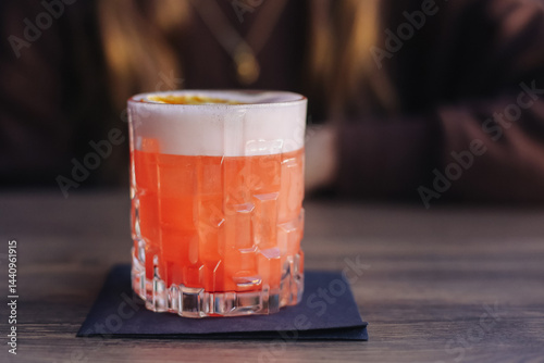Refreshing pink cocktail in elegant glass. Summer drink with foam. Vibrant colorful beverage. Tasty fruity refreshment. Modern bar atmosphere. Closeup of stylish cocktail presentation.