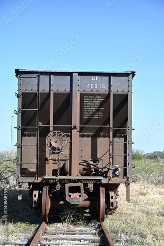Abandoned Freight Railcar on Overgrown Track under Clear Sky