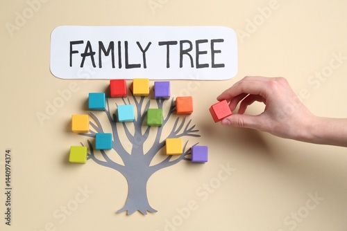 Woman making family tree with colorful cubes on beige background, top view