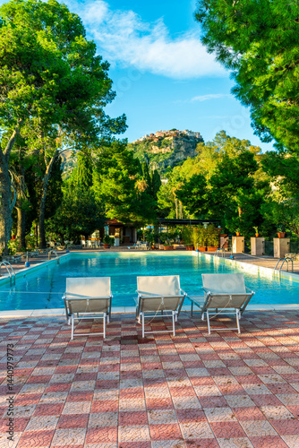 three white desk chairs or chaise lounge with blue swimming pool and hotel green garden on backgeound of vacation summer landscape