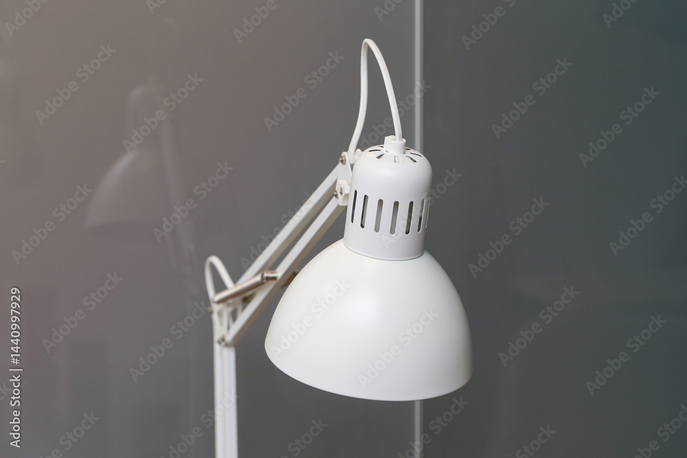Minimalist white desk lamp. Modern workspace accessory. Simple lighting design. Bright light source. Contemporary interior element. Clean and stylish desk lamp. Elegant home office decor.