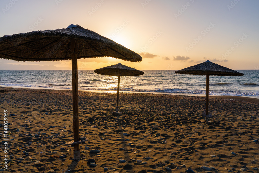 Straw beach umbrellas against background of sunset sky convey atmosphere of rest, romance, peace, end of warm day by sea. Straw beach umbrellas against background of sunset sky convey atmosphere of rest, romance, peace, end of warm day by sea.