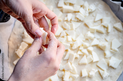 Obraz na płótnie Close-up scene of female hands. Adding a mixture of three cheeses - mozzarella, parmesan and gorgonzola to the dough on the kitchen countertop. Making homemade pizza with three types of cheese - femal w salonie