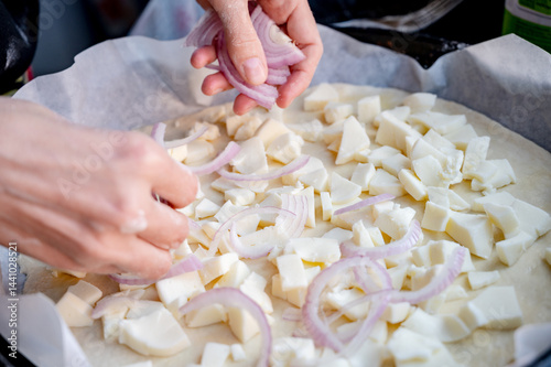 Obraz na płótnie Close-up scene of female hands. Adding onion to dough on kitchen countertop. Making homemade pizza with three types of cheese – female hands in action. w salonie