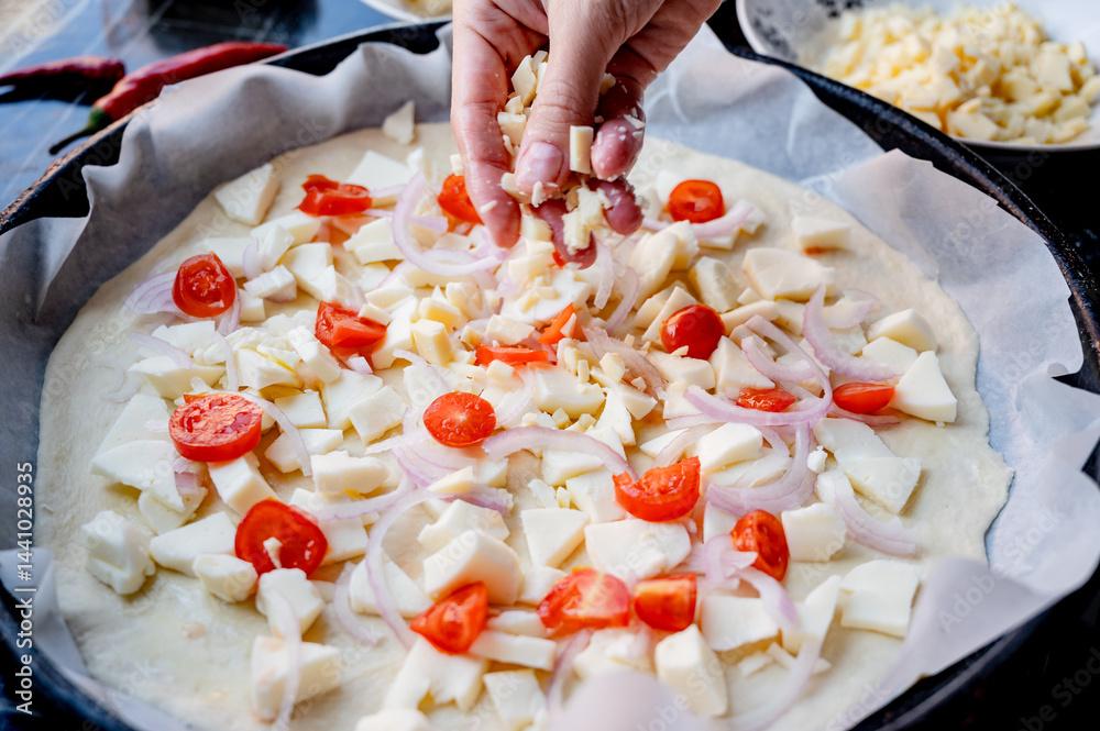 Close-up scene of female hands. Adding a mixture of three cheeses - mozzarella, parmesan and gorgonzola to the dough on the kitchen countertop. Making homemade pizza with three types of cheese - femal