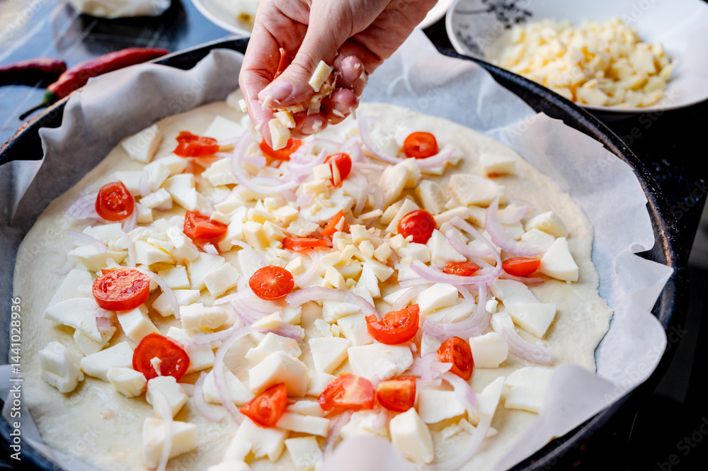 Close-up scene of female hands. Adding a mixture of three cheeses - mozzarella, parmesan and gorgonzola to the dough on the kitchen countertop. Making homemade pizza with three types of cheese - femal