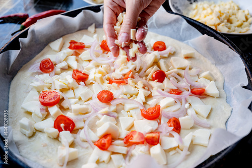 Obraz na płótnie Close-up scene of female hands. Adding a mixture of three cheeses - mozzarella, parmesan and gorgonzola to the dough on the kitchen countertop. Making homemade pizza with three types of cheese - femal w salonie