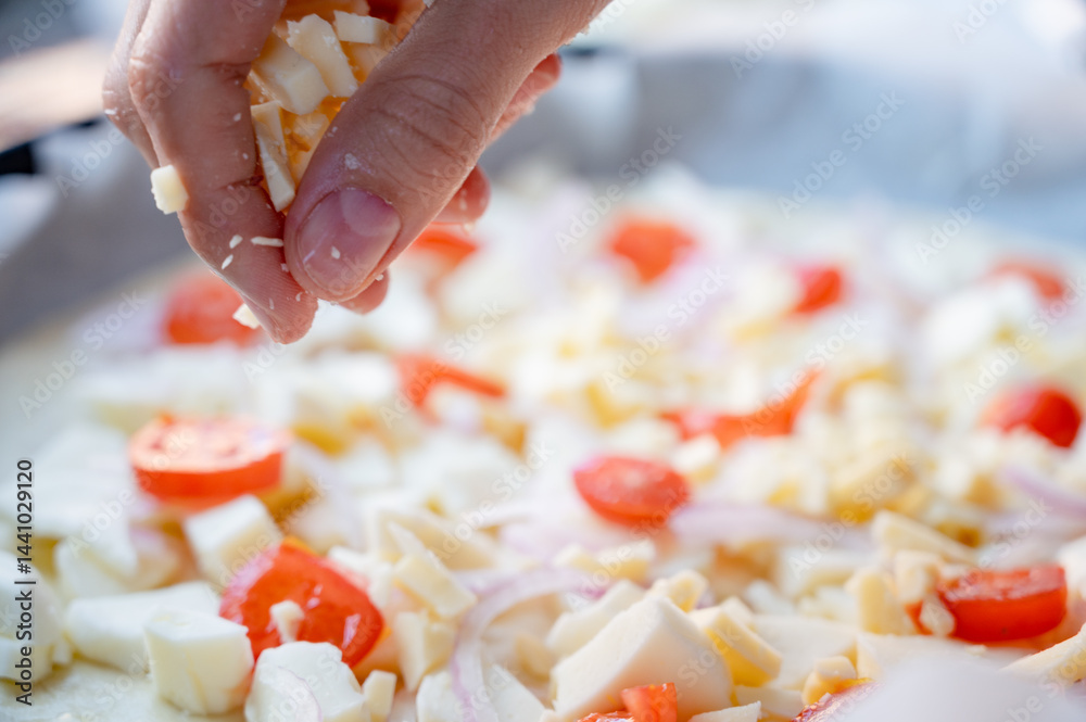 Close-up scene of female hands. Adding a mixture of three cheeses - mozzarella, parmesan and gorgonzola to the dough on the kitchen countertop. Making homemade pizza with three types of cheese - femal