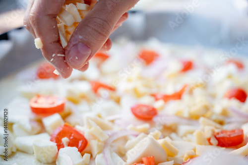 Obraz na płótnie Close-up scene of female hands. Adding a mixture of three cheeses - mozzarella, parmesan and gorgonzola to the dough on the kitchen countertop. Making homemade pizza with three types of cheese - femal w salonie