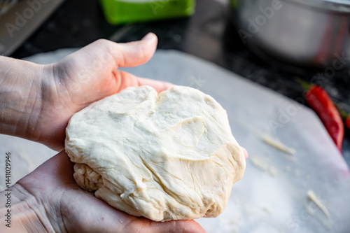 Obraz na płótnie Homemade Pizza Preparation with Three Cheeses – Female Hands in Action. A warm, close-up scene of a woman’s hands preparing homemade pizza dough on a kitchen countertop. Photo recipe. w salonie