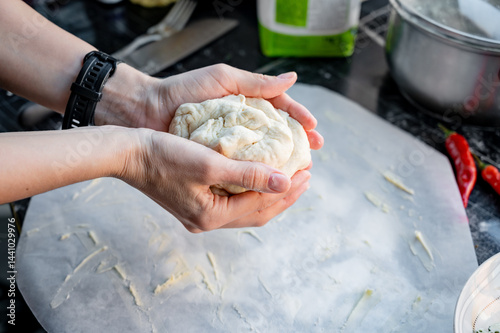 Obraz na płótnie Homemade Pizza Preparation with Three Cheeses – Female Hands in Action. A warm, close-up scene of a woman’s hands preparing homemade pizza dough on a kitchen countertop. Photo recipe. w salonie