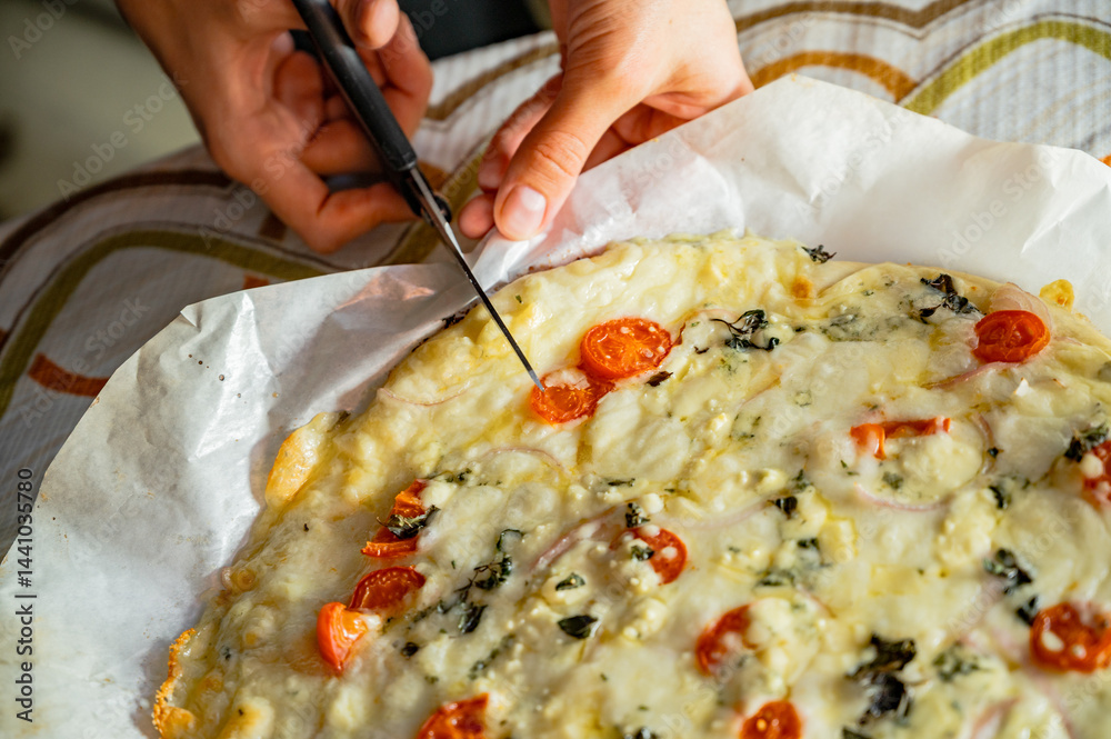 Cutting fresh homemade pizza with scissors