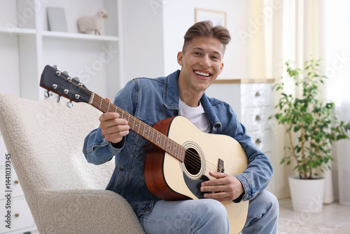 Obraz na płótnie Happy man playing guitar on armchair indoors w salonie