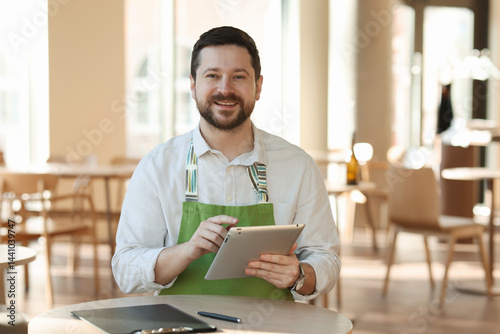 Smiling business owner with tablet in his cafe