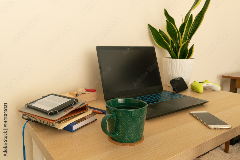 Fototapeta premium Home workspace with various items such as laptop, cup, potted plant, etc. Work from home, remote work.