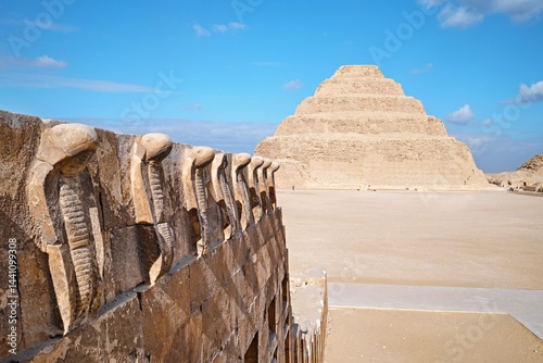Saqqara, Egypt - January 2, 2024: The Pyramid of Djoser (or Djeser and Zoser), or Step Pyramid and the cobra wall of the in the Saqqara necropolis