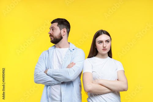 Resentful couple with crossed arms on yellow background