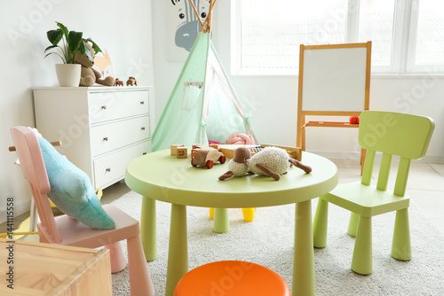 Interior of light playroom with toys, teepee and whiteboard in kindergarten