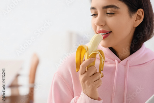 Young woman eating banana a...
