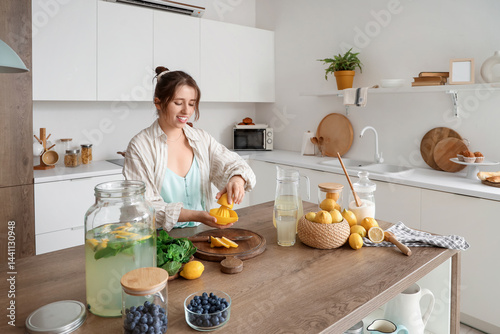 Young woman squeezing lemon...