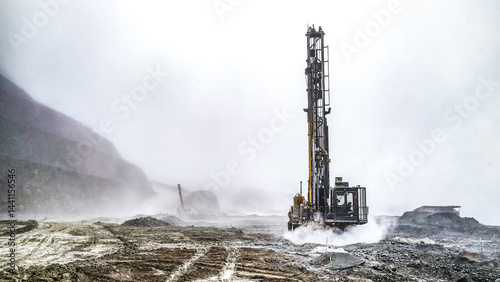 Mining Heavy Equiptment, Mining drilling machine working at open pit in a cloud of dust for blasting activities