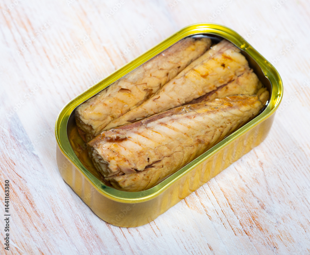 Open can of mackerel fillets preserves in sunflower oil on wooden table