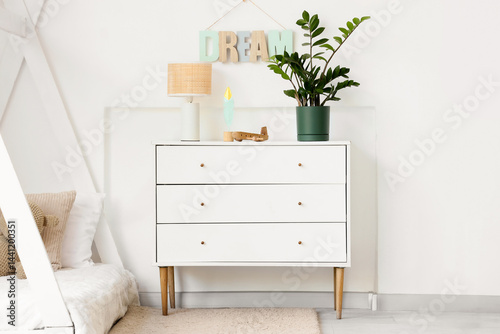 Obraz na płótnie Chest of drawers with toy plane, lamp and houseplant in light nursery w salonie
