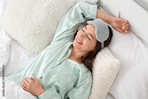 Morning of happy young woman lying in bedroom, top view